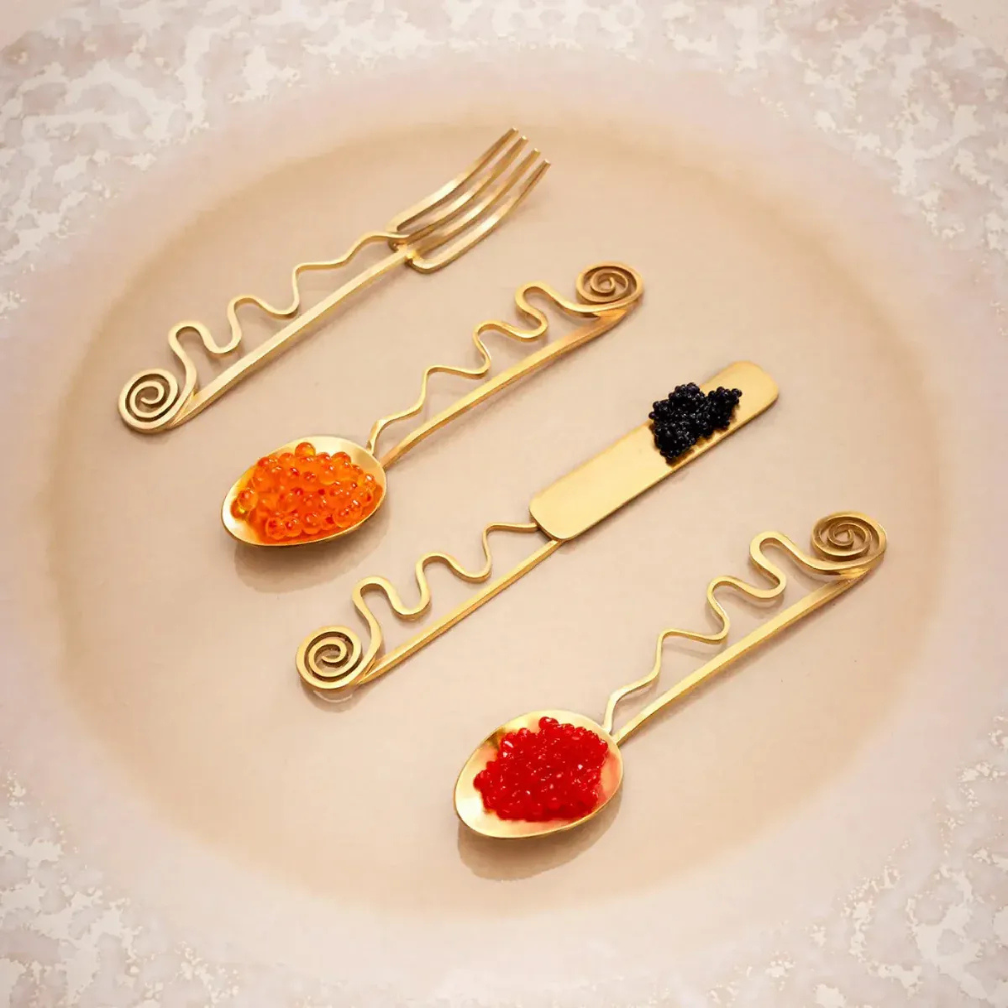 Set of gold caviar spoons with caviar on a beige plate